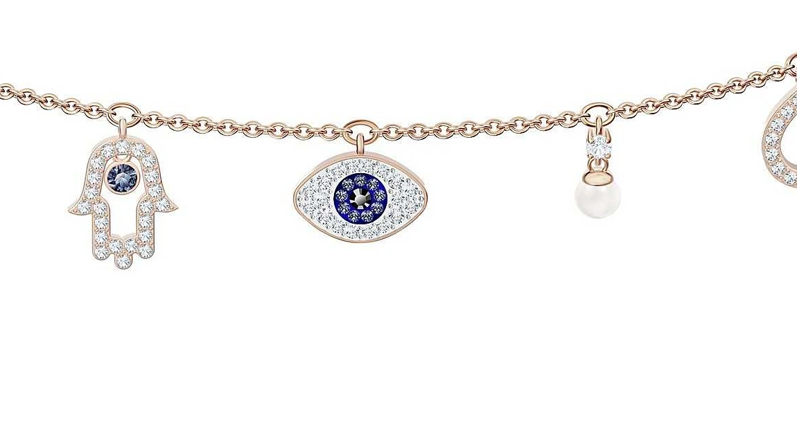 Gros plan des breloques du collier Swarovski Symbolic : main de Fatma pavée de cristaux, œil protecteur bleu et perle, chaque pierre sertie individuellement