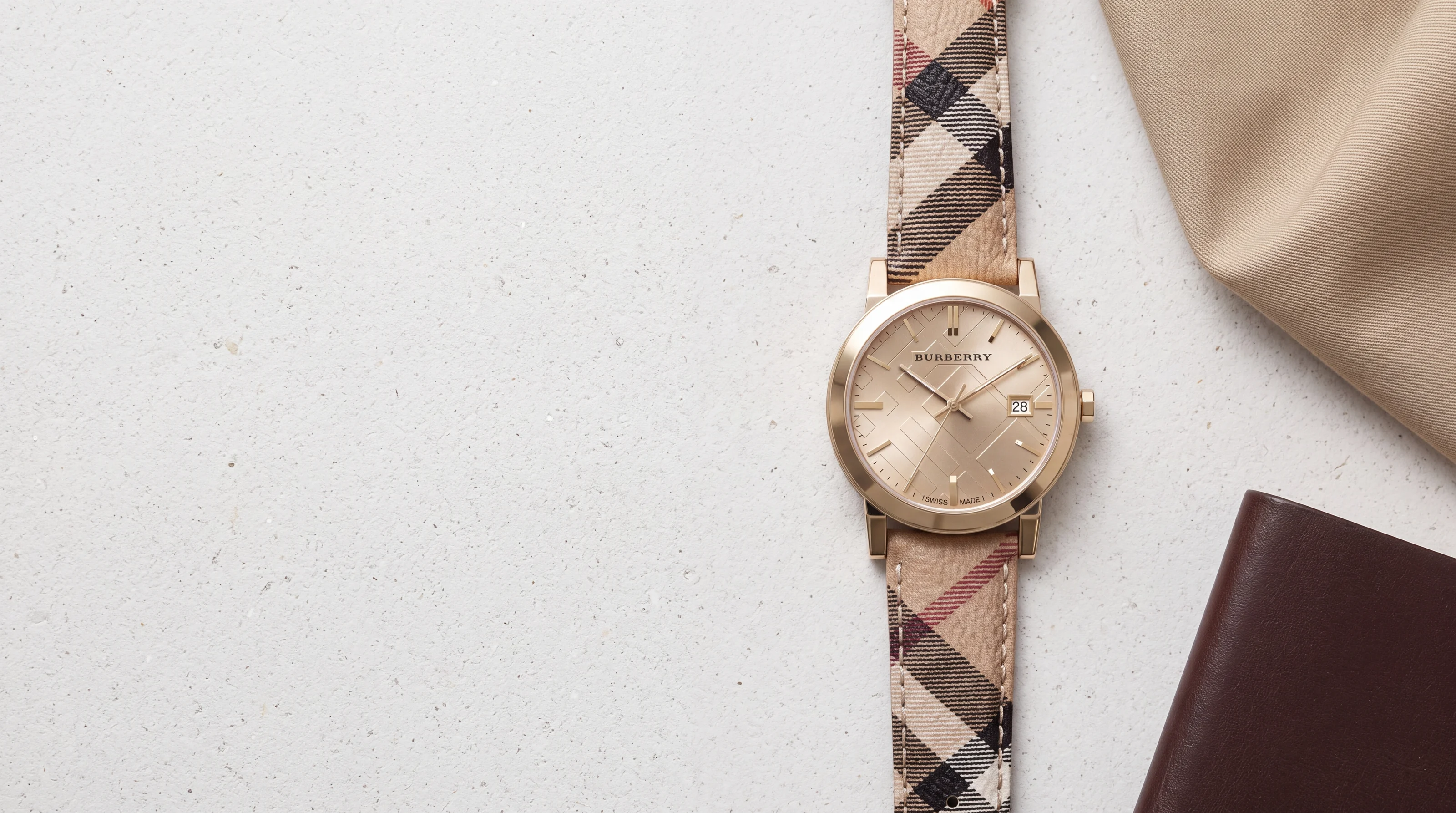 Burberry The City BU9026 watch, light gold case and check canvas strap, on pale Portland stone
