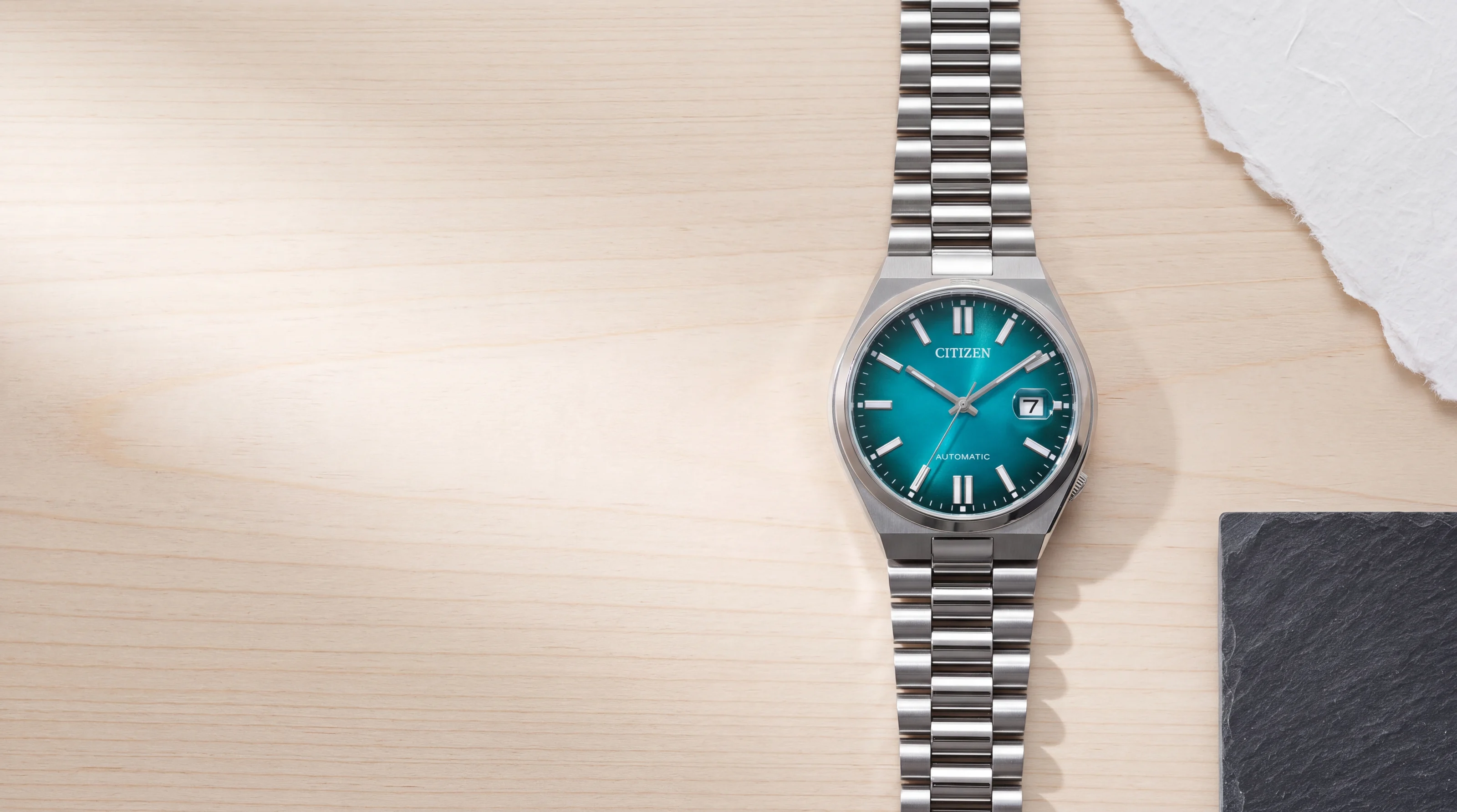 Citizen Tsuyosa NJ0151-88X automatic watch, teal dial, integrated steel bracelet, on pale hinoki wood