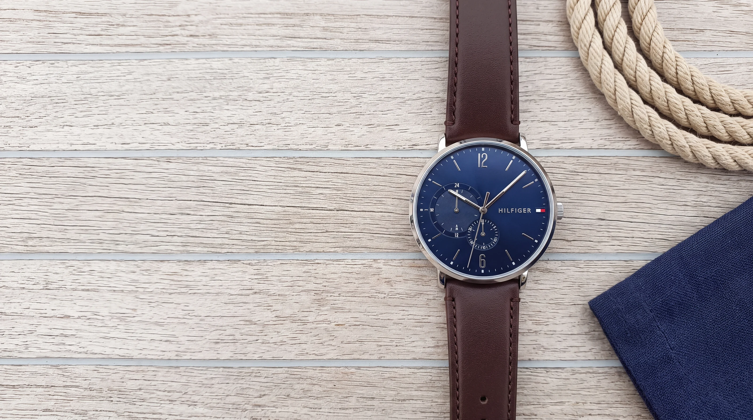 Tommy Hilfiger 1791508 steel watch with navy dial and brown leather strap on a teak deck