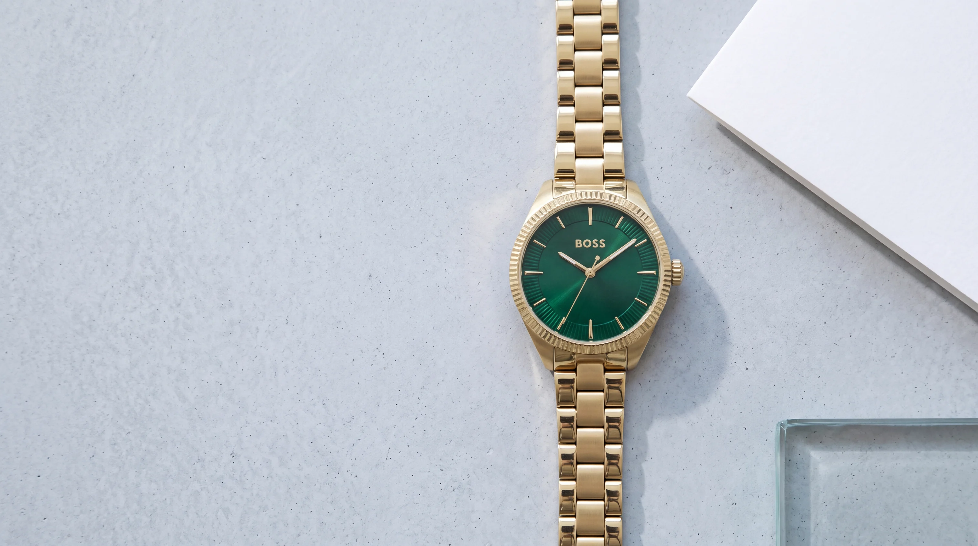 HUGO BOSS Sage 1502729 gold-tone women's watch with green dial and fluted bezel on pale grey polished concrete
